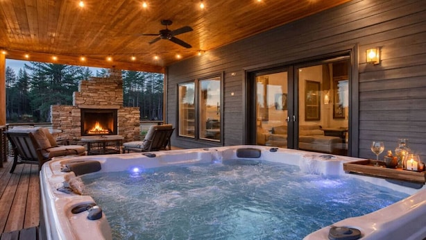 Un jacuzzi con asientos, una chimenea de piedra y una terraza con mobiliario exterior.