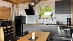 A compact kitchen with a built-in oven, a microwave, a sink, and a dining area with a table and chairs.