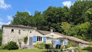 A stone house with blue shutters, a tiled roof, and a garden with a lawn and a few plants. - Roc de Lapalue - Three Bedroom Villa, Sleeps 6 (Montcuq)