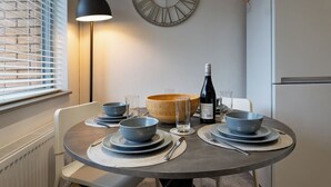 A dining table with four bowls, a wine bottle, and a clock on the wall.