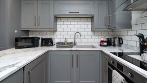 A kitchen with grey cabinets, a microwave, a toaster, a sink, and a coffee maker.