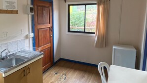 A kitchen with wooden cabinets, a sink, a window with curtains, and a white table.