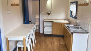 A compact kitchen with a dining table, chairs, and a built-in sink.