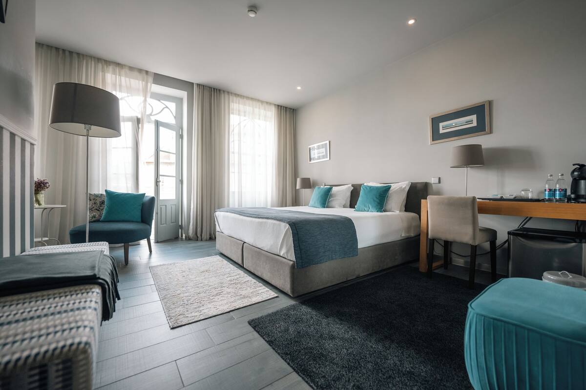Une chambre d’hôtel moderne avec un grand lit, un bureau, une chaise et une petite table.