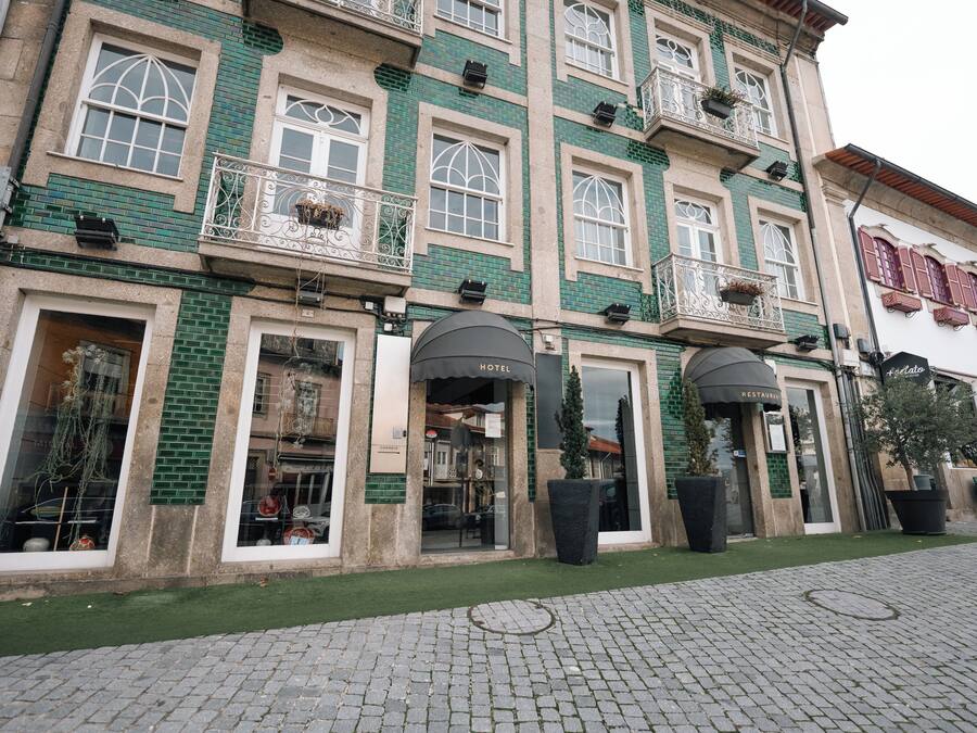 A hotel with multiple stories, large windows, and a green facade.