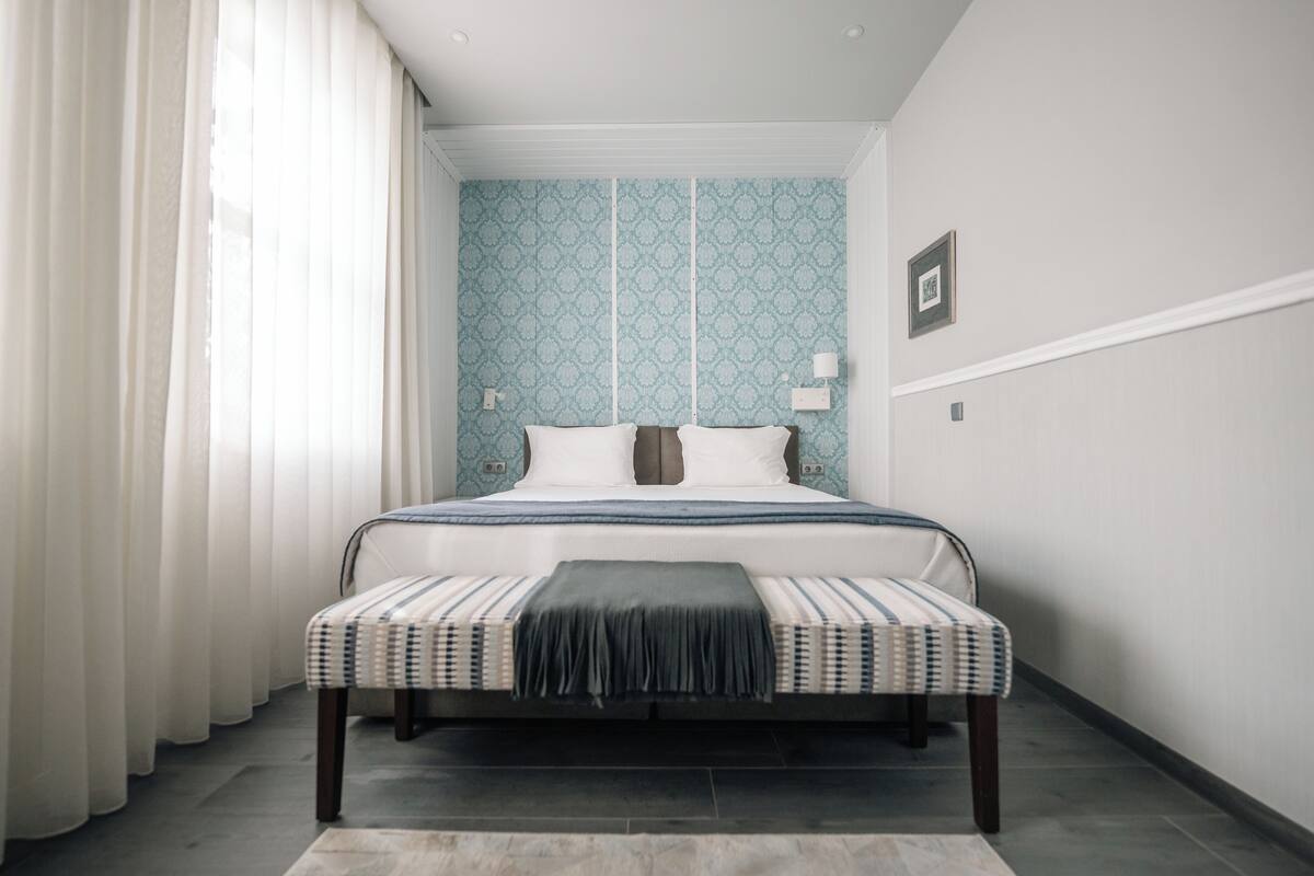 Une chambre à coucher avec un lit, des rideaux, un mur à motifs et une table de chevet.