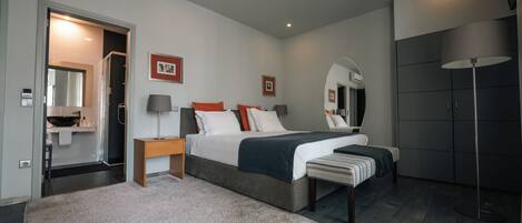 A modern bedroom with a large bed, bedside tables, a mirror, and a wardrobe.