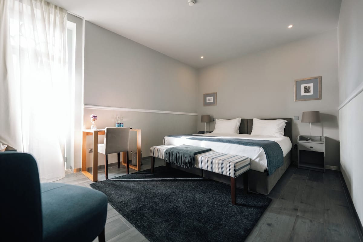 Une chambre d’hôtel moderne équipée d’un lit, de tables de chevet, d’un bureau et d’une chaise.