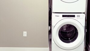 A stacked washer and dryer unit in a room with a plain wall and a wooden floor. - Charming Apartment with fitness room and in lovely Birmingham (Birmingham)