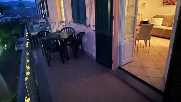 A balcony with outdoor seating, a sliding glass door leading to an interior living area, and a view of the street and hills in the background. - Casa Marta in Lucca within walking distance of downtown and hospital, private parking (Lucca)