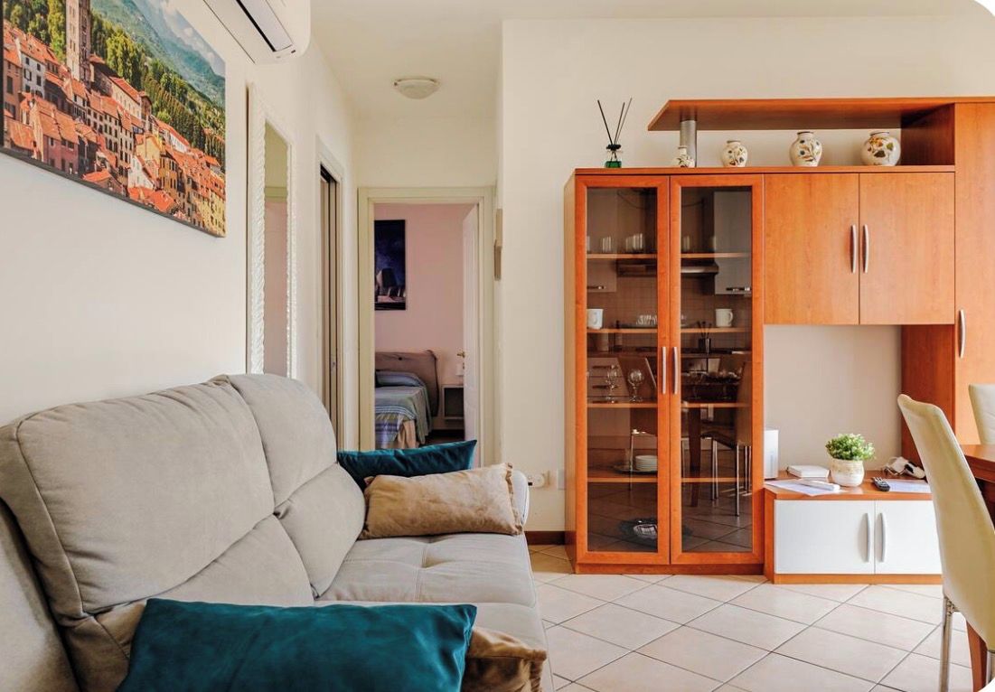 A living room with a sofa, a cabinet with glass doors, and a dining area with a chair.
