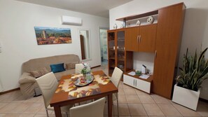 A dining area with a table set for two, a sofa, and a cabinet with glass doors. - Casa Marta in Lucca within walking distance of downtown and hospital, private parking (Lucca)