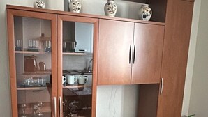 A wooden cabinet with glass doors containing kitchenware and a white cabinet below. - Casa Marta in Lucca within walking distance of downtown and hospital, private parking (Lucca)