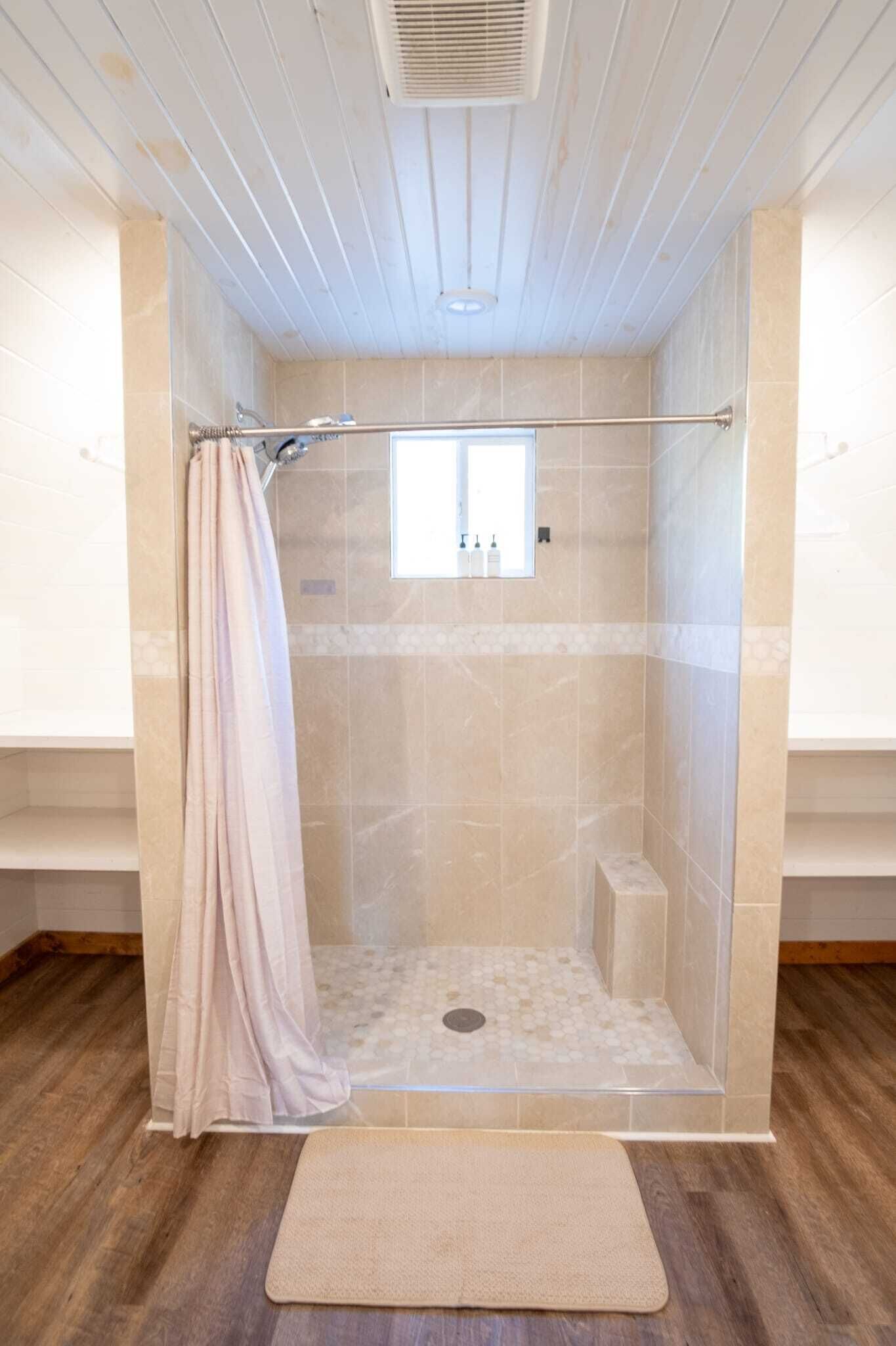 A shower with a glass door, a towel rack, and a window.