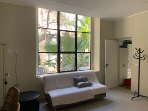 Una habitación con un ventanal grande, un sofá, una silla y un perchero.