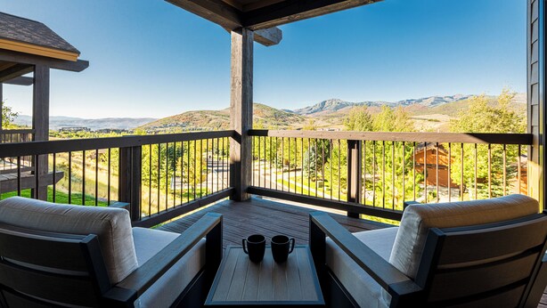 A covered outdoor seating area with a table and two chairs, overlooking a mountainous landscape. - Park City Summer Retreat | Near Hiking, Biking & Jordanelle (Kamas)