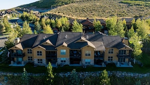 A multi-story residential building with a stone facade, multiple balconies, and a driveway leading to a parking area. - Park City Summer Retreat | Near Hiking, Biking & Jordanelle (Kamas)