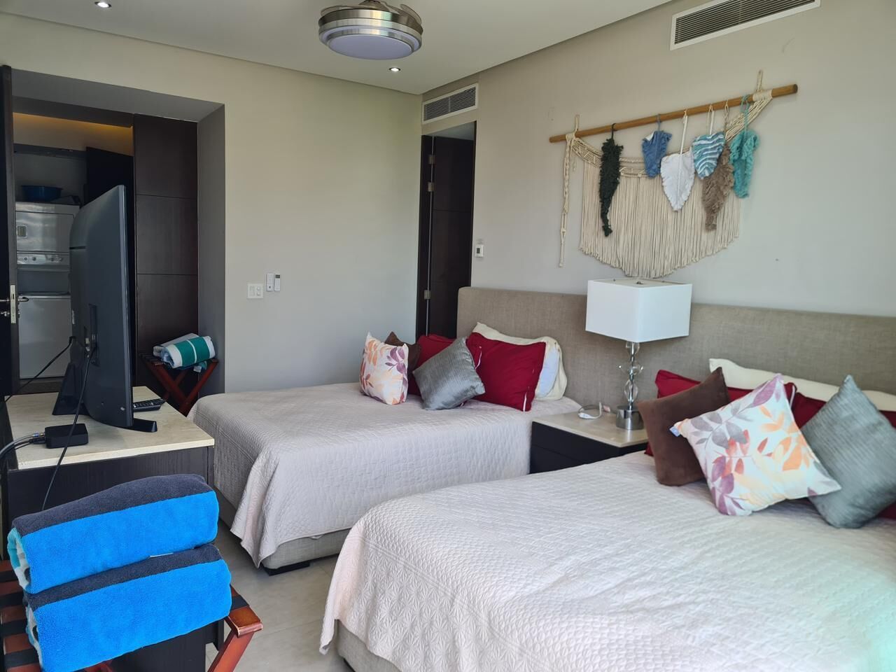 Une chambre d’hôtel avec deux lits, un bureau avec un ordinateur, une tél évision et une kitchenette.