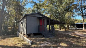 Eine kleine Holzhütte mit roter Tür, umgeben von Bäumen.
