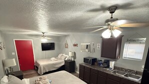 Ein gemütliches Schlafzimmer mit zwei Betten, einer Küchenzeile und einem Deckenventilator.