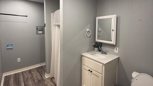 Ein Badezimmer mit Holzboden, einem weißen Waschbecken, einem Spiegel darüber und einer Toilette.