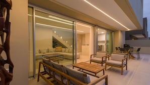 A modern living area with a sofa, chairs, and a table. There is a staircase leading to an upper level.