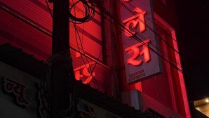 Een gebouw met een verticaal bord waarop tekst in een niet-Latijns schrift staat, waarschijnlijk een bedrijf of gelegenheid aanduiding.