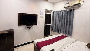 Een slaapkamer met een bed, een aan de muur bevestigde televisie, een plafondventilator en een airconditioning.
