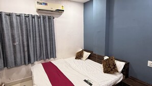 Een slaapkamer met een bed, een plafondventilator, een airconditioner en een raam met gordijnen.