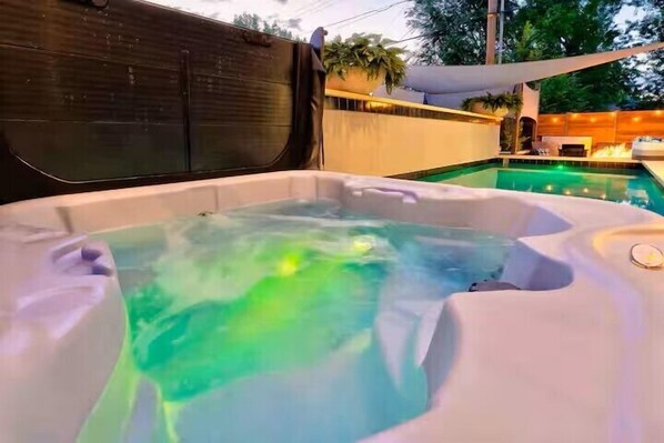 Ett bubbelbad med en pool i bakgrunden.