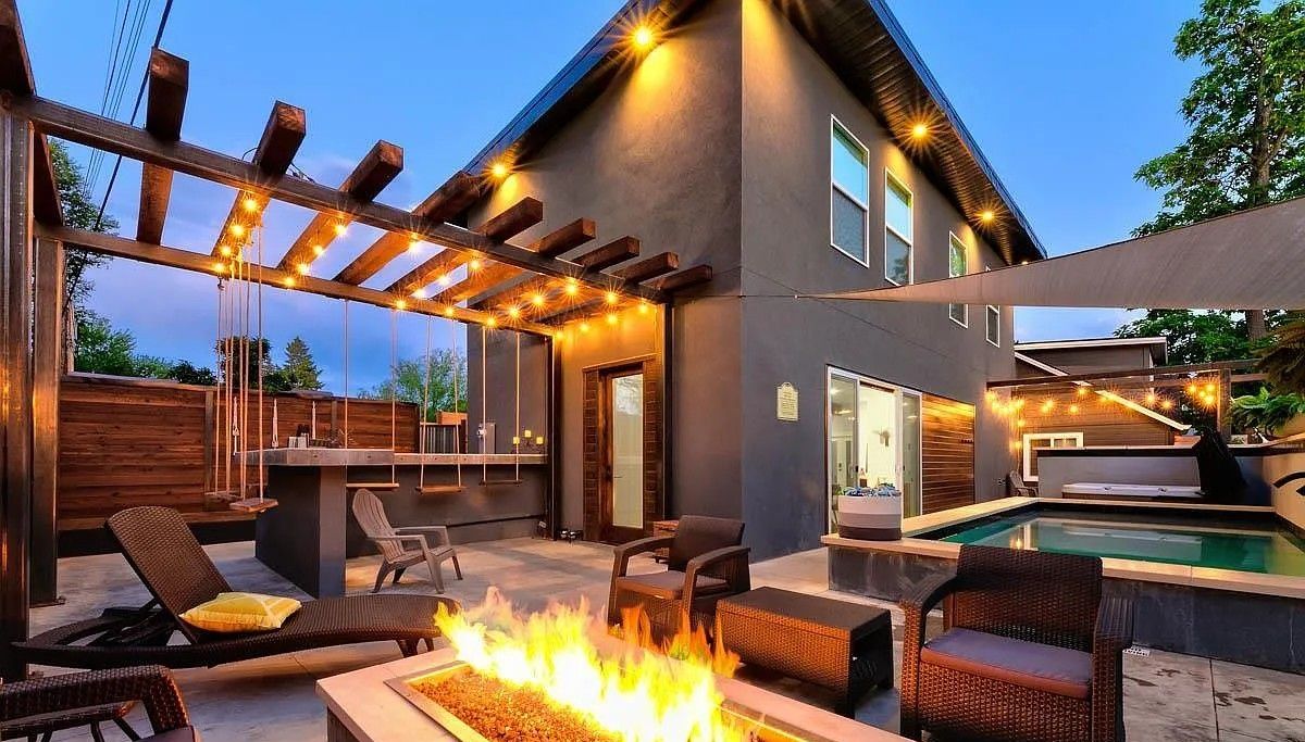 A modern outdoor patio with a fire feature, seating, and a pool.