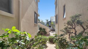 A narrow pathway flanked by buildings with a clear sky above. - Nautilus 2 Ground Floor Apartment (Hawks Nest)