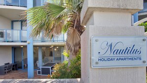 A sign for Nautilus Holiday Apartments with a balcony and outdoor seating area. - Nautilus 2 Ground Floor Apartment (Hawks Nest)