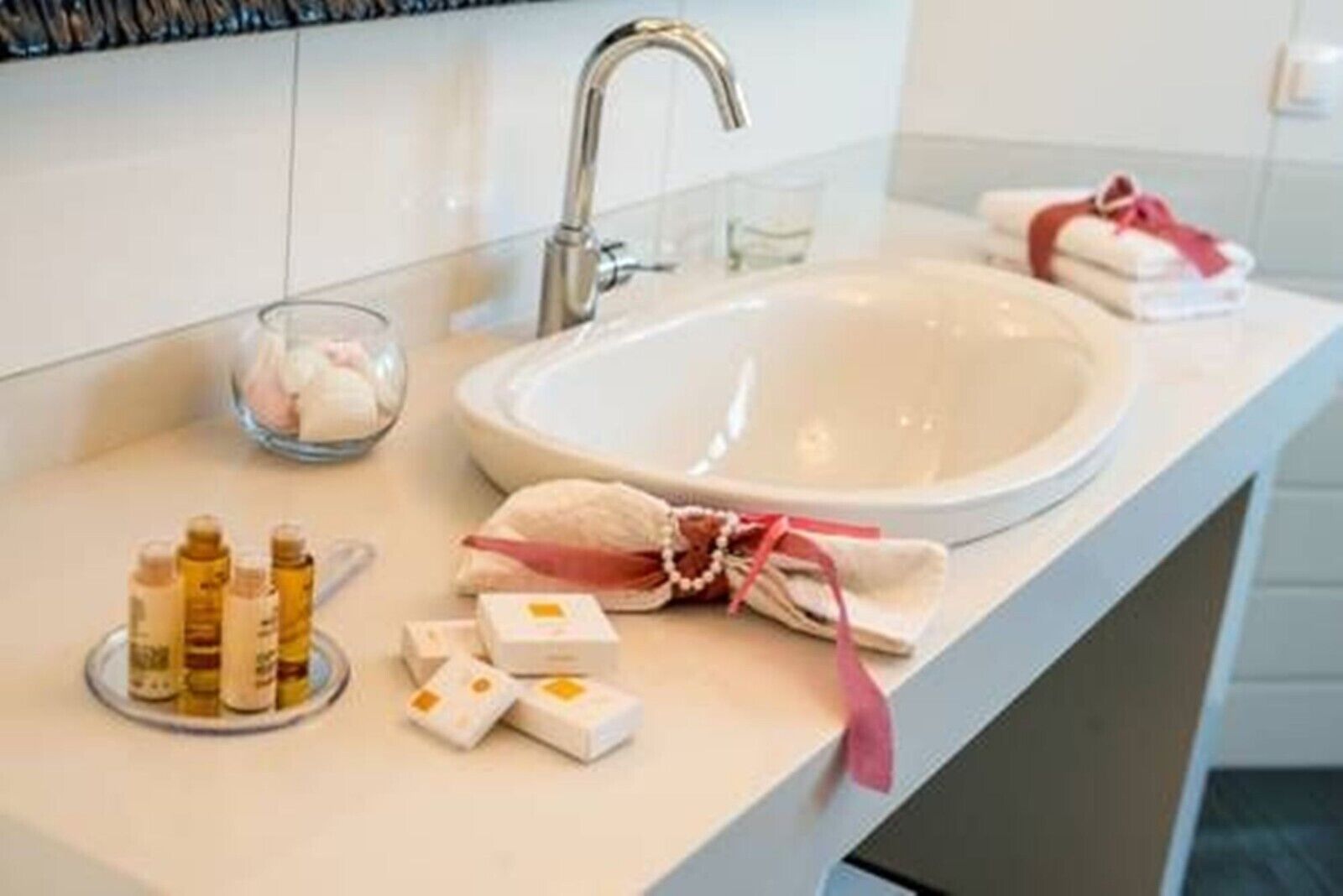 Een badkamer met een grote wastafel, toiletartikelen en handdoeken.