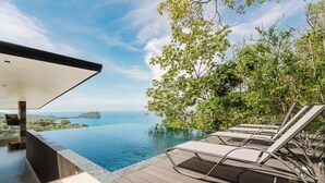 An infinity pool with lounge chairs, a wooden deck, and a view of the sea and islands. - Villa Zest 4 bedroom Villa • Rooftop Infinity Pool & Ocean Views (manuel antonio)