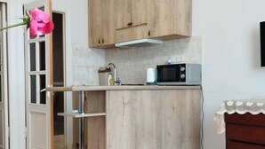A compact kitchen with wooden cabinets, a microwave, and a sink. - 21 Apartment in Yerevan 01 (Yerevan)