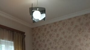 A room with a bed, floral wallpaper, and a ceiling light fixture. - 21 Apartment in Yerevan 01 (Yerevan)