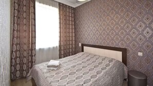 A bedroom with a patterned wallpaper, a bed with a patterned bedspread, a hanging light fixture, and a window with curtains. - 21 Apartment in Yerevan 3 (Yerevan)