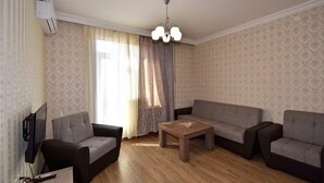 A living room with a sofa set, a coffee table, and a TV. - 21 Apartment in Yerevan 1 (Yerevan)