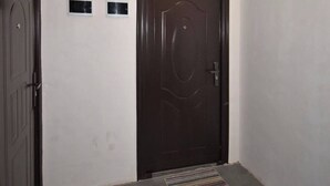 A room with a dark wooden door, a small window, and a textured carpet. - 21 Apartment in Yerevan 1 (Yerevan)