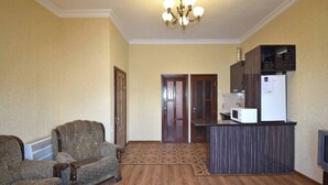 A compact living space with a kitchenette, a dining area, and a seating area with a sofa and armchair. - 21 Apartment in yerevan 02 (Yerevan)