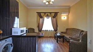 A living room with a sofa, a coffee table, a washing machine, and a TV. - 21 Apartment in yerevan 02 (Yerevan)
