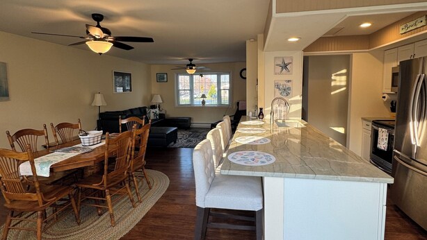 A spacious kitchen with a central island, wooden dining table, and chairs, along with a refrigerator and oven. - “It's A Shore Thing” located in beautiful Easton, MD. Close to MD & DE beaches. (Easton)