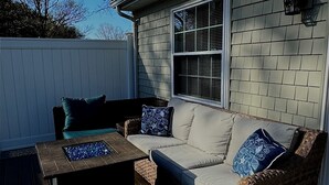 A covered outdoor seating area with a sofa and a coffee table, a wooden deck, and a white fence. - “It's A Shore Thing” located in beautiful Easton, MD. Close to MD & DE beaches. (Easton)