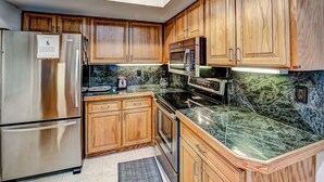 Una cucina con mobili in legno, elettrodomestici in acciaio inossidabile e un piano di lavoro in granito.
