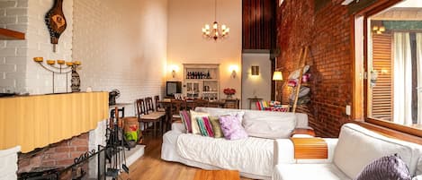 Una sala de estar acogedora con un sofá blanco, una mesa de centro de madera y una chimenea de ladrillo.