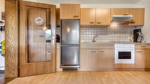Une cuisine moderne avec des meubles en bois, un réfrigérateur en acier inoxydable, un four et un revêtement mural en carreaux.