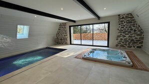 Ein Wellnessbereich mit Whirlpool und kleinem Pool, Steinwänden und einem großen Fenster.