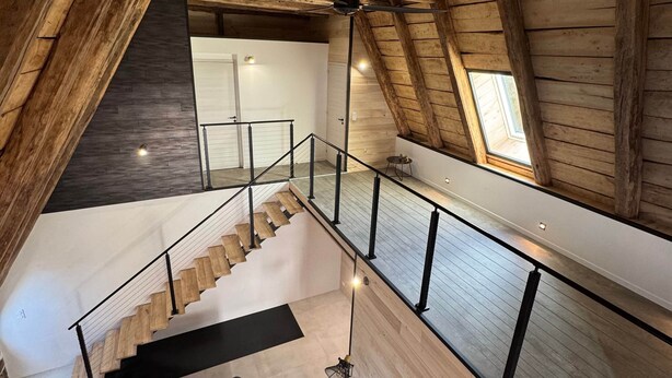 Ein modernes Loft mit Holzvertäfelungen, einer Treppe zu einer erhöhten Ebene und einem Oberlicht.