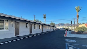 Un motel avec une rangée de chambres, un parking et une montagne en arrière-plan.